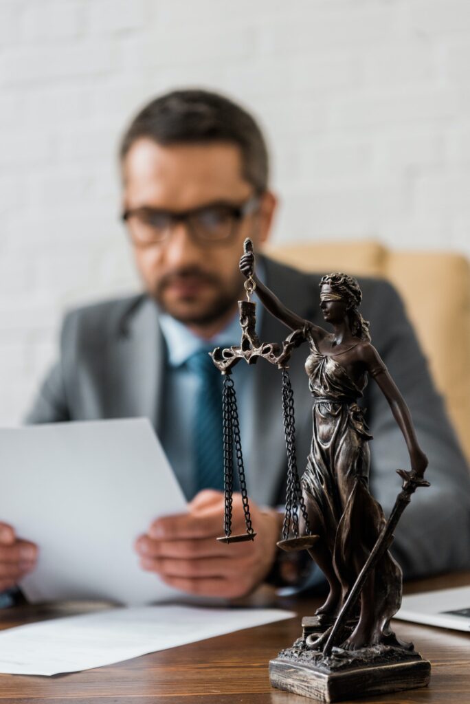 close-up view of lady justice statue and male lawyer working behind