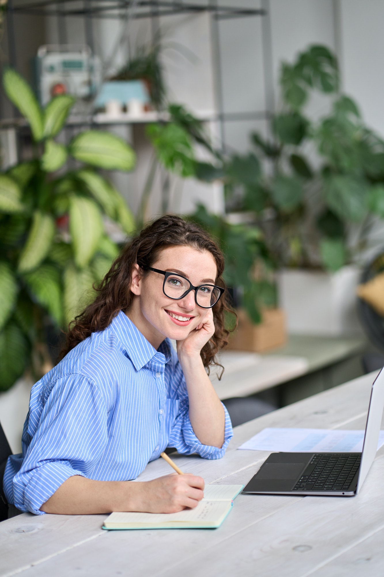 Young business woman working at desk with laptop. Vertical