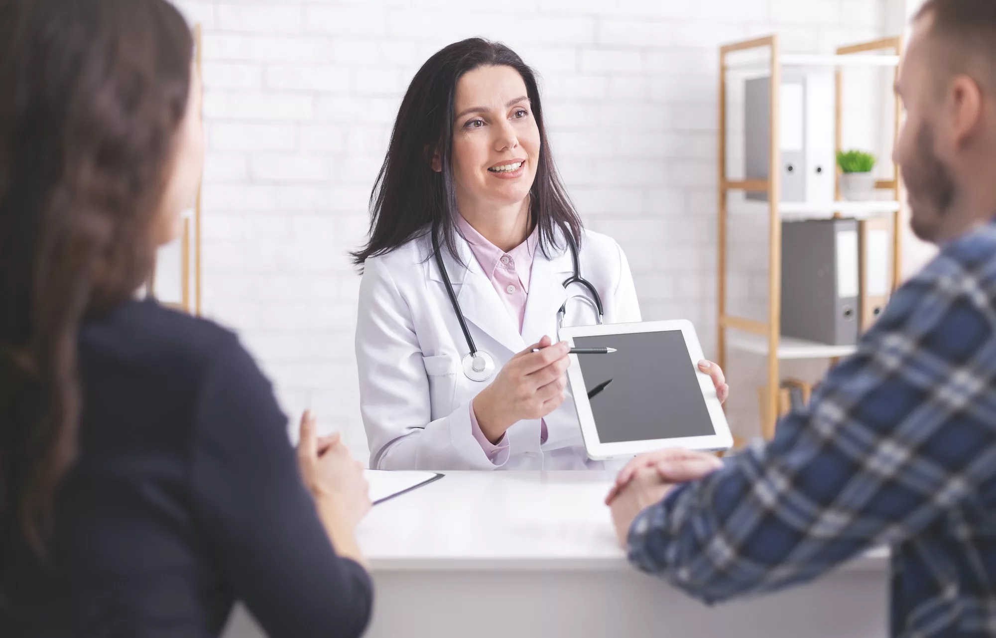 Doctor showing test results on digital tablet to married patients